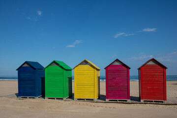 Fototapeta na wymiar Colorful wooden changing rooms on the beach of Cullera, Valencia, Spain
