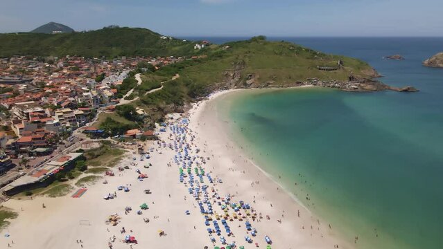City and the coast of the sea with the hill and rocks with several people enjoying a sunny day on the beach with the umbrellas a beautiful place Arraial do Cabo Brazil