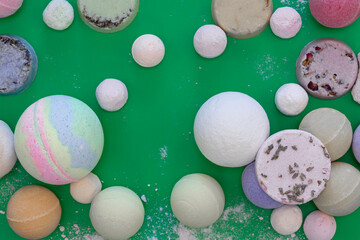 Multicolored bath bombs on a green background, top view.