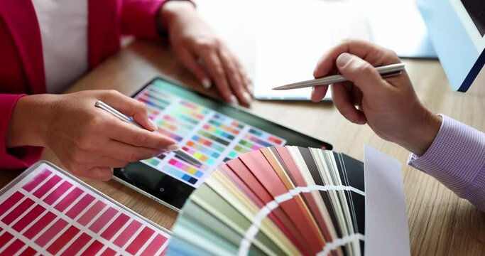 Designer advises client and shows color sample in color palette and on tablet