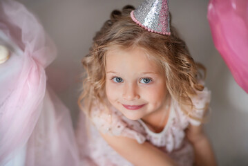 Cheerful mischievous girl. Holiday Birthday. Beautiful little girl laughs. The girl is dressed in a dress and sneakers. Fashion baby. Five year old baby. Portrait of a beautiful little girl