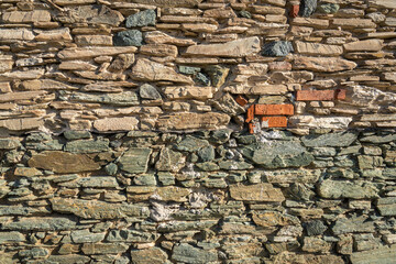 Eine alte verwitterte Steinmauer mit vielen kleinen und großen Steinen als Hintergrund