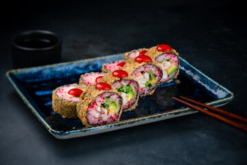 Set of tempura sushi rolls with shrimp, cream cheese, avocado, flying fish caviar and sauce.