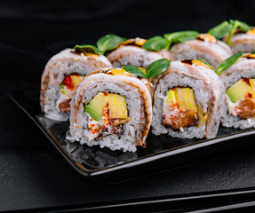 Eel sushi rolls on black plate