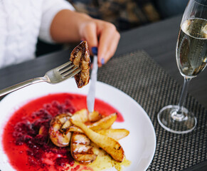 woman eating meat and drink champagne in a restaurant