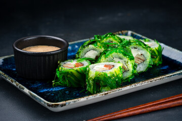 Set of Japanese sushi rolls with salmon, cream cheese, tamago omelet in marinated chuka seaweed and sauce.