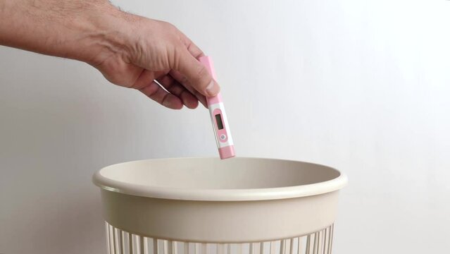 A plastic thermometer for measuring body temperature is thrown into the trash. Disposal and recycling of plastic.