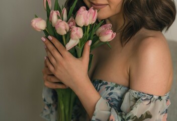 Obraz na płótnie Canvas Spring tulips in woman`s hands. Beautiful young woman with tulip bouquet. Spring flowers, pink tulips in female hands. Easter, Birthday, Mother's, Women's, Wedding Day concept.