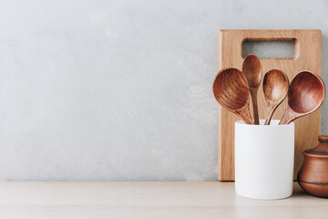 Kitchen utensils background. Wooden spoons and cutting board on light background with copy space.