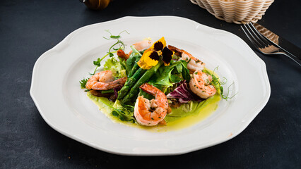 Green salad with shrimps, asparagus, lettuce and green sauce.