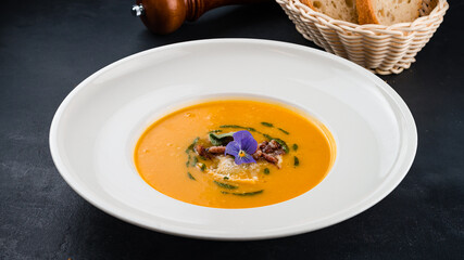 Fresh pumpkin cream soup with champignons and greens.