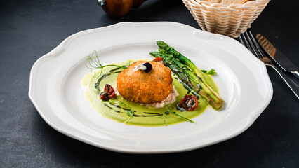 Snack breaded shrimp balls with asparagus, tomatoes and green sauce.
