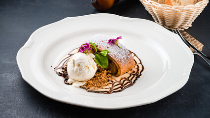 Piece of apple strudel with a scoop of ice cream, mint and powdered sugar.