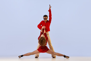 Young flexible couple of dancers in bright retro fashion clothes, stage costumes dancing over light...