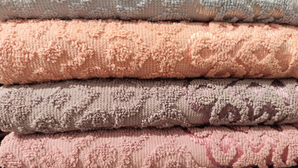 Abstract background and texture from a stack of colored soft terry towels. Lots of colorful bath towels stacked on each other. Cotton towels for hotels, home, bathroom, kitchen
