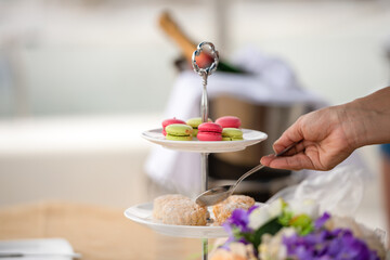Obraz na płótnie Canvas Afternoon tea stand decorate catering banquet table services with macaroon snacks and appetizers, fresh fruits on bartender counter in hotel restaurant. Snack foods serving in party event.
