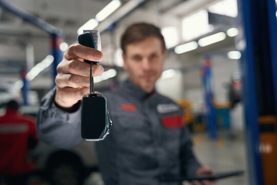 Portrait of mechanic giving car keys after repair