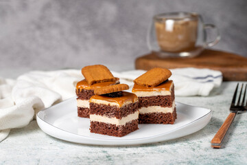 Small dessert cakes. Caramel petit four on a white plates in dark background. Biscuit french petit...