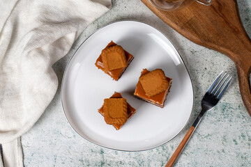 Small dessert cakes. Caramel petit four on a white plates in dark background. Biscuit french petit four cake. Top view