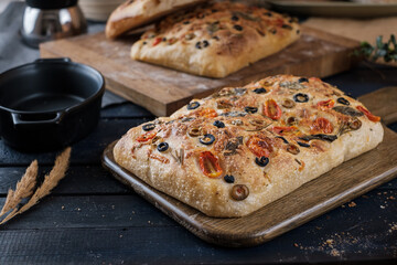 Focaccia with olive tomatoes and rosemary. Homemade Italian Sourdough Bread on white cafe table. - 579360354