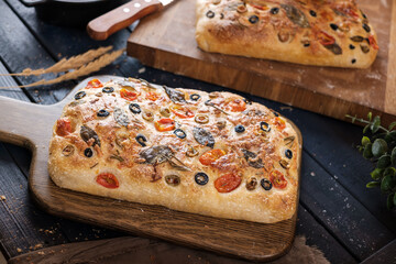 Focaccia with olive tomatoes and rosemary. Homemade Italian Sourdough Bread on white cafe table. - 579360355