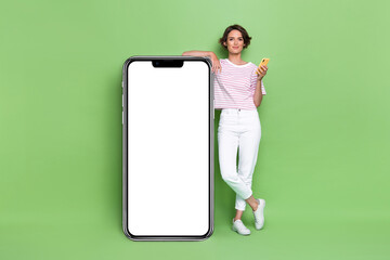 Photo of pretty lady empty space demonstrate present big telephone banner promo use modern device gadget isolated on green color background