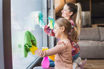 Happy daughter and mother cleaning house together.