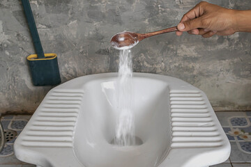 Man using baking soda to clean toilet bowl