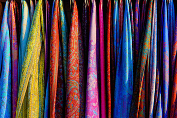 Colorful scarves hang on display in a street small shop