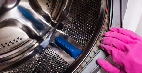 Dirty rubber gasket with mold on the washing machine. Cleaning the washing machine. Close-up. Copy...