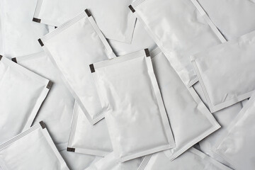 pile of blank white sachet packets full frame background, close-up of scattered food or medicine...