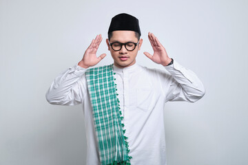 Asian muslim man in white prayer clothes doing the "Takbirotul Ihram" , a movement to start prayer