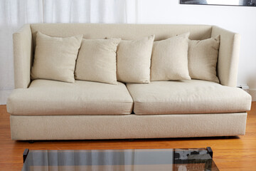 White textured Modern remake of a mid-century modern design sofa. Couch with nubby, soft, and subtle herringbone fabric covers. Interior view with long white curtains and glass-top coffee table. 
