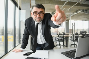 Fototapeta premium Angry businessman sitting at the table and screaming over.