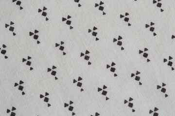 Fabric with a repeating abstract geometric pattern. Black shapes on white cloth. 