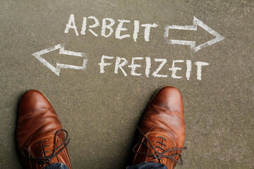 The words Arbeit and Freizeit (German for work and spare time) written on the floor with arrows pointing in opposite directions