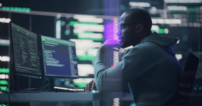 Black Male Programmer Working in Monitoring Room, Surrounded by Big Screens Displaying Lines of Programming Language Code. Portrait of Man Creating a Software. Abstract Futuristic Coding Concept