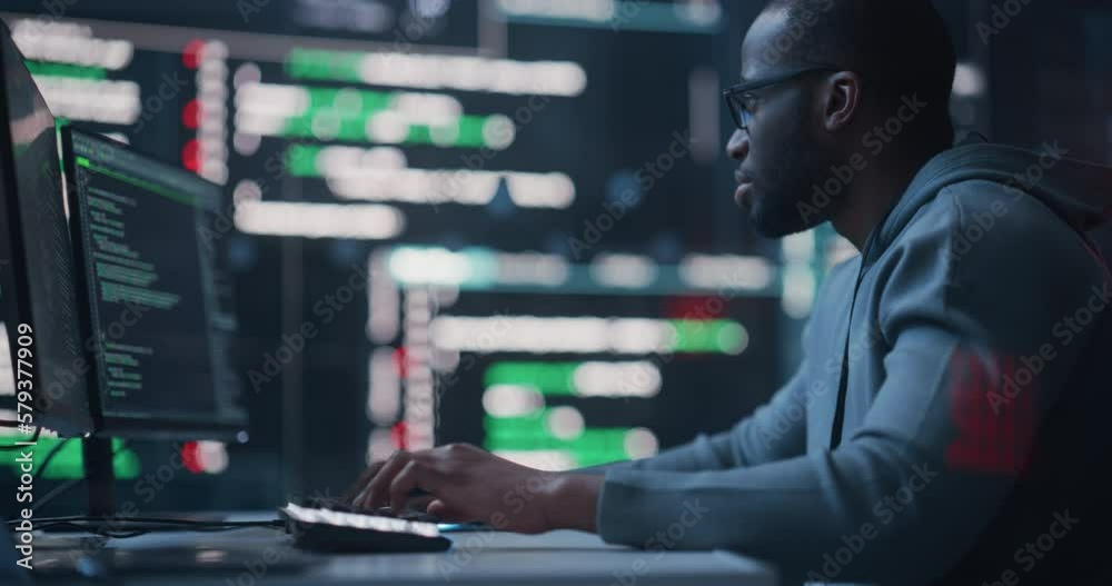 Aufkleber Dolly Shot of a Black Male Programmer Working in a Monitoring Control Room, Surrounded by Big Screens Displaying Lines of Programming Language Code. Portrait of a Man Creating a Software and Coding
