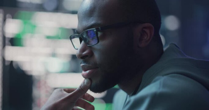 Zoom In, Close Up Portrait of Black Man Working on Computer, Lines of Code Language Reflecting on his Glasses. Male Programmer Developing New Software, Coding, Managing Cybersecurity Project