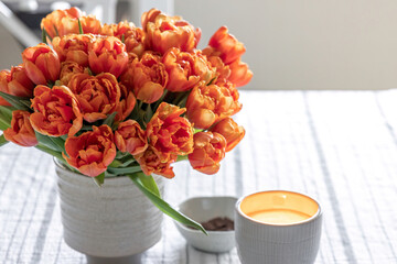 Spring composition with a bouquet of orange tulips in the interior of the house.