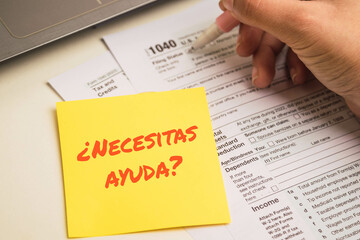 woman hand filling 1040 tax forms , Need help text in spanish on sticky notes United States tax form, a laptop on a desk. US individual income tax return. Accountant working with 