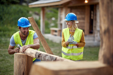 Builders are chatting while working on a wooden cottage in the forest. Construction, building,...