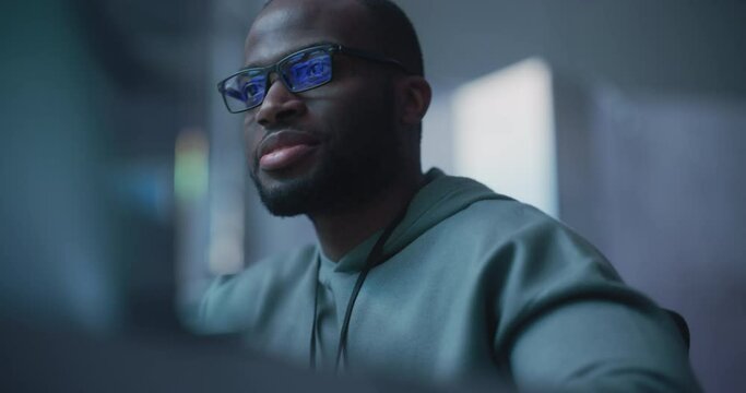Black Male Developer Smiling Happily After Successfully Typing on Computer a Functioning Software Code. Professional Programmer Creating a Mobile App, Screen Display Reflected on his Glasses