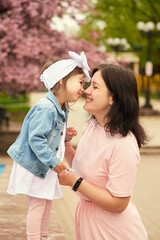 Mother and daughter play, laugh in a blooming garden