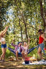 Group of young backpackers, having picnic in forest. Celebrating together, having fun. Young man...