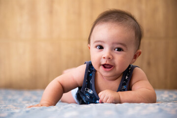 baby lying on a bed, looking forward and smiling.