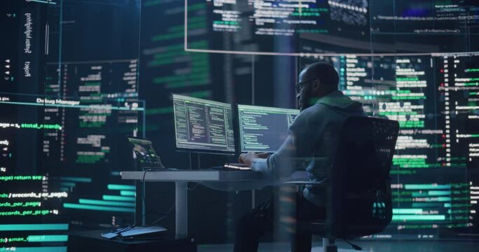 Medium Shot of a Man Working as a Developer, Surrounded by Big Screens Displaying Lines of Code in a Monitoring Room. Black Male Programmer Using Desktop Computer, Analysing Data, Creating AI Software