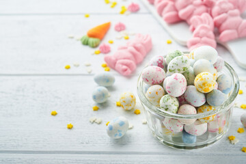 Sweet Easter concept. Sweet Easter kids holiday assortment marshmallows rabbit, chocolates easter eggs, candies, bunny, snacks  on white wooden background. Flat lay Easter decoration idea. Mock up.