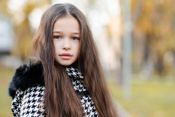 Fototapeta premium Cute teenage girl 14-15 year old with long blonde hair autumn jacket in park outdoor. Look at camera. Teenagerhood.