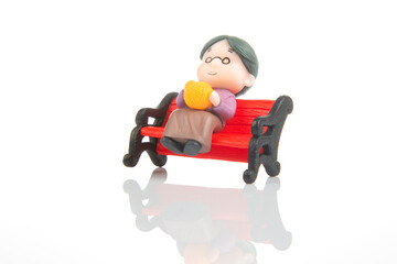 miniature people. figures for the concept. lonely grandmother sitting on a bench